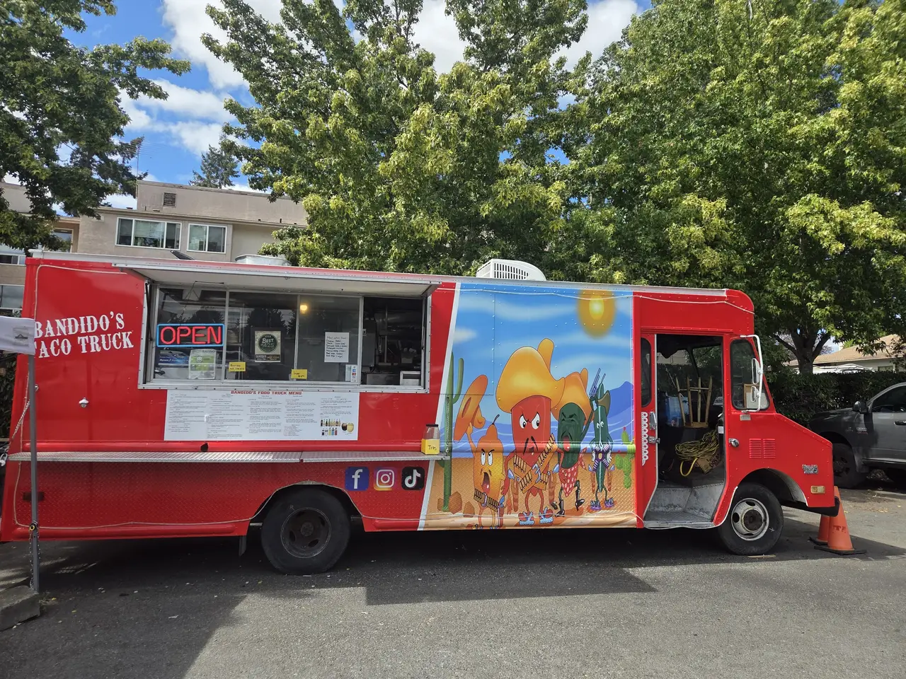 Bandido's Taco Truck, a bright red food truck with a hand-painted desert mural, parked with its order window open and OPEN sign lit